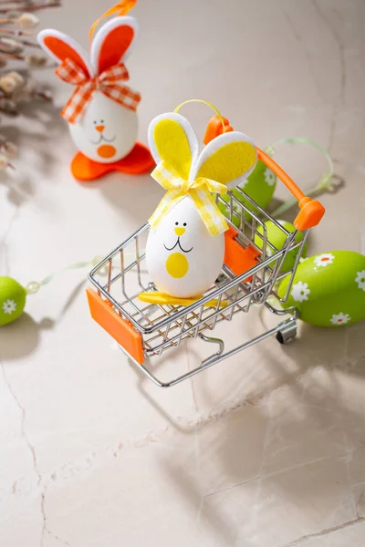 Easter funny bunny in shopping cart, green easter eggs