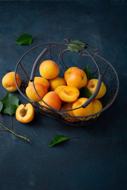 Karanlık yüzeyde sepetin içinde taze kayısı hasadı.