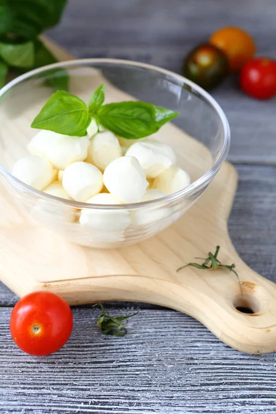 Mozzarella en un tazón sobre tabla de cortar —  Fotos de Stock