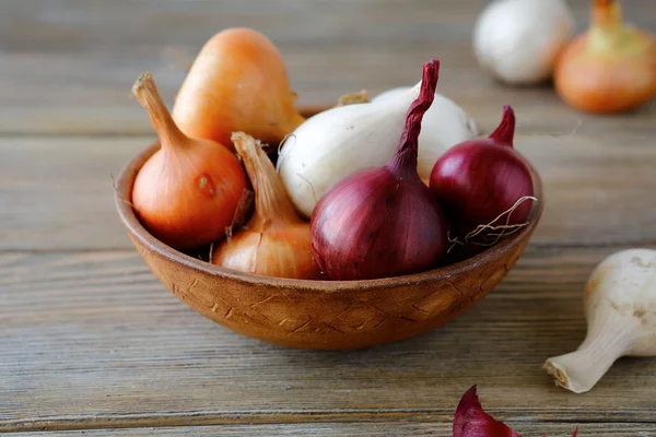 Sweet onions and dried husk in a bowl on wooden boards — Stock Photo, Image