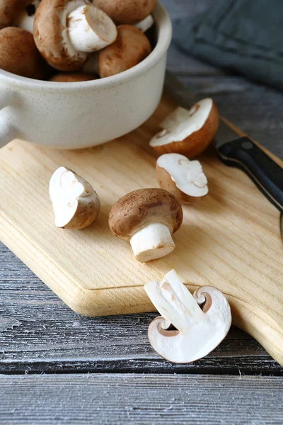 Champignons in a bowl on cutting board — Stock Photo, Image