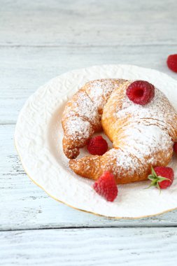 kruvasan ile beyaz tabakta ahududu