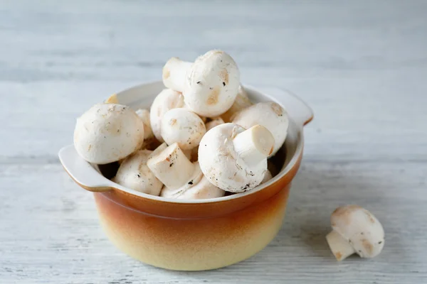 Raw champignons in a bowl on wooden boards — Stock Photo, Image