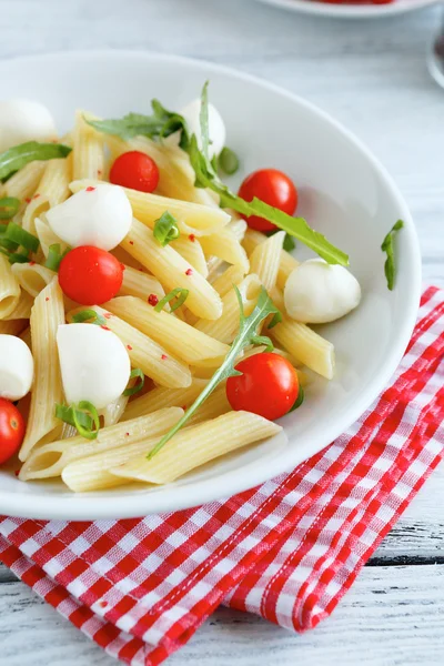 Penne su un piatto bianco con pomodori e mozzarella — Foto Stock