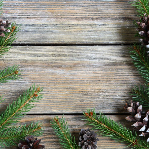 Різдвяна рамка з сосновою гілкою і шишками на дерев'яних дошках — стокове фото