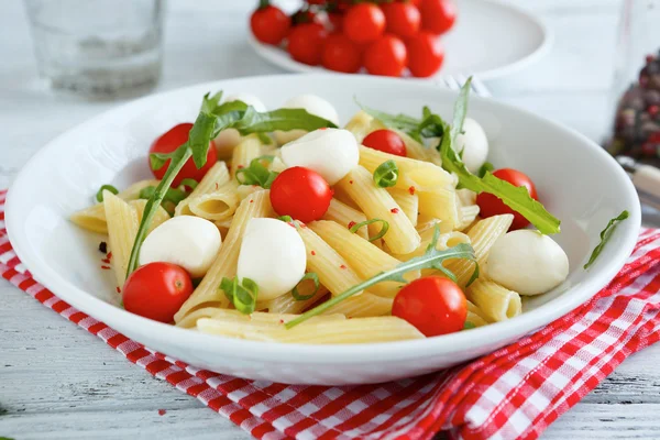 Паста з овочами і скибочками сиру моцарелла в тарілці — стокове фото