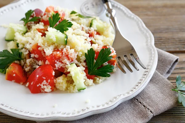 Salade avec couscous et légumes sur une assiette blanche — Photo