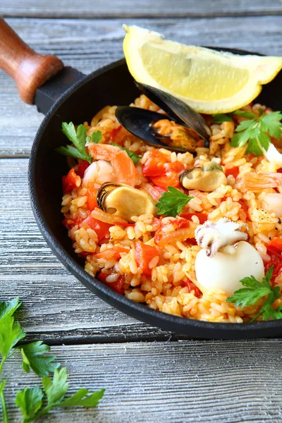 Paella com frutos do mar e salsa em uma frigideira — Fotografia de Stock