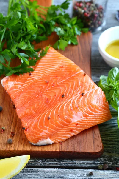 Filete de pescado rojo con perejil y albahaca en una tabla de cortar — Foto de Stock