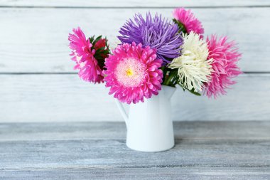 Beyaz bir vazo içinde renkli Aster buket