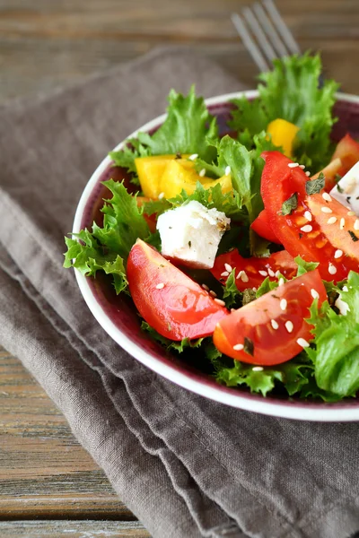 Salad with tomatoes, cheese and greens in a bowl on napkin — Stock Photo, Image