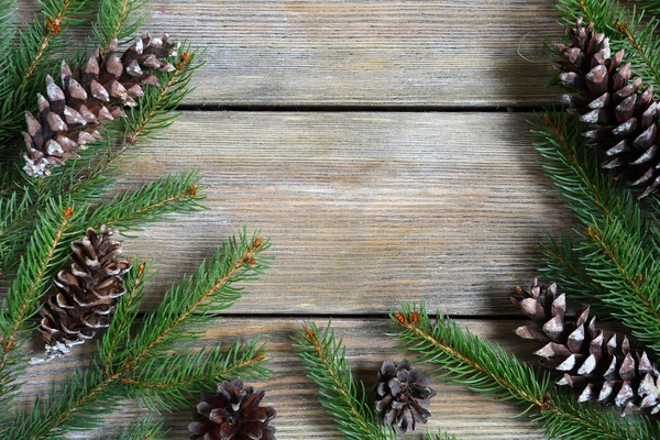 Різдвяна рамка з зеленою сосновою гілкою з конусами на дошках — стокове фото