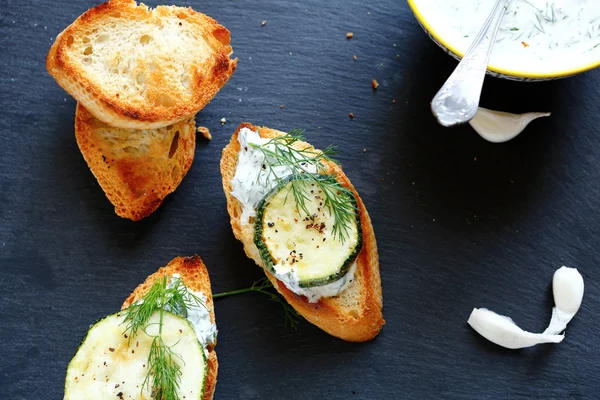 Bruschetta en segmenten van gebakken stokbrood op leisteen — Stockfoto