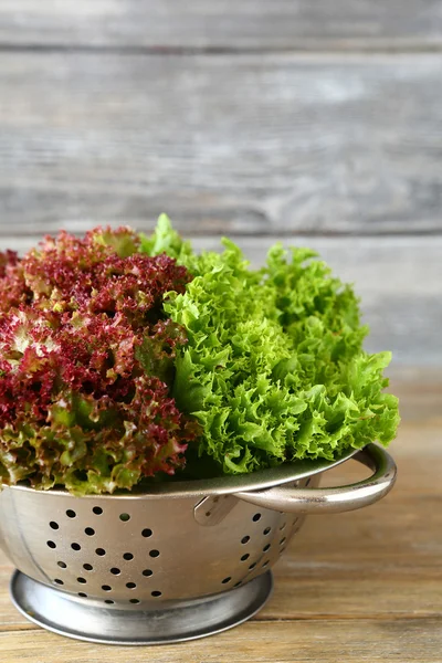 Green salad in a colander on wooden boards — Stock Photo, Image