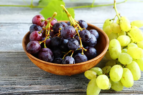 Bunches of grapes in bowl on wooden boards — Stock Photo, Image