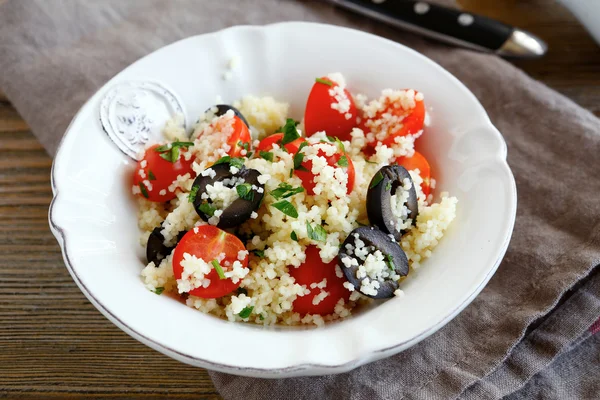 Вкусный салат кускус с овощами и оливками на тарелке — стоковое фото