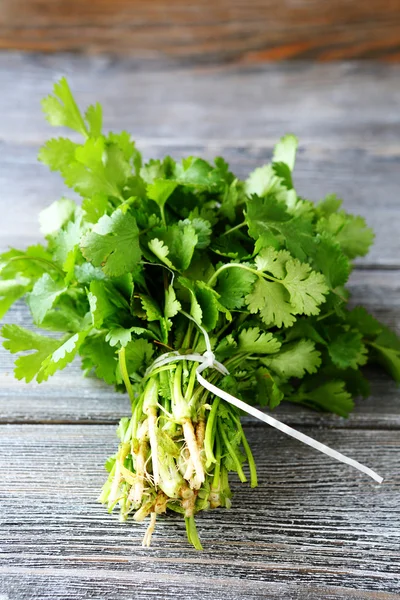 Manojo de cilantro fresco en tablas de madera — Foto de Stock