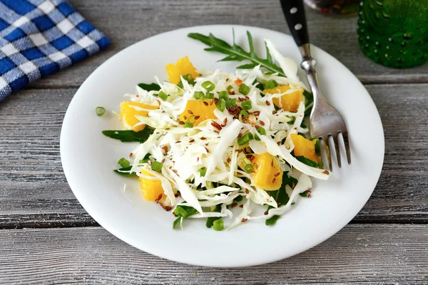 Легкая капустная зелень и апельсины на тарелке — стоковое фото
