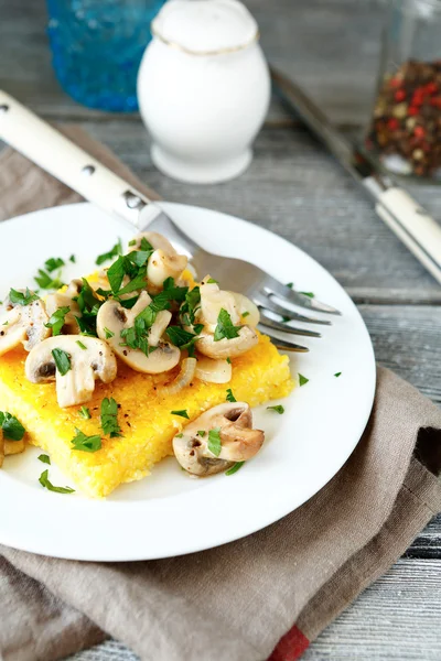 Polenta com cogumelos fritos em uma chapa branca — Fotografia de Stock