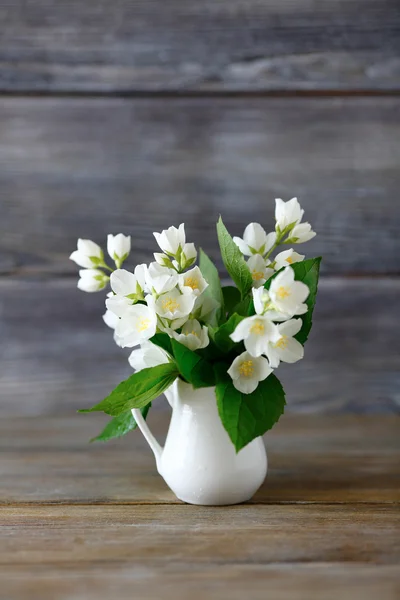 Flores blancas en un jarrón sobre una superficie de madera — Foto de Stock