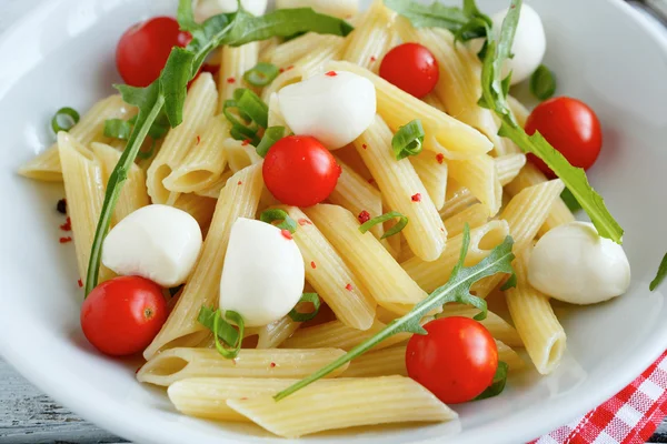 Penne with tomatoes and slices of mozzarella cheese — Stock Photo, Image