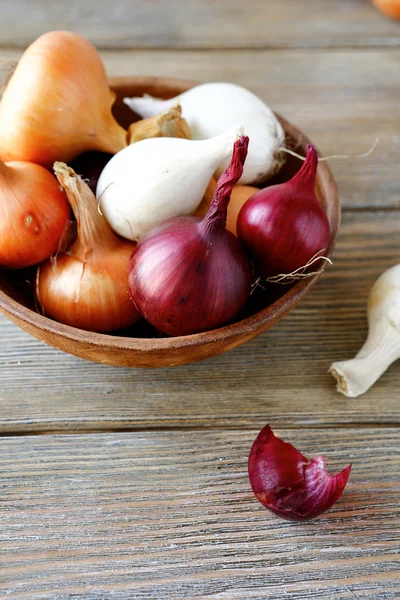 Sweet onions of different varieties and dried husk in a bowl — Stock Photo, Image