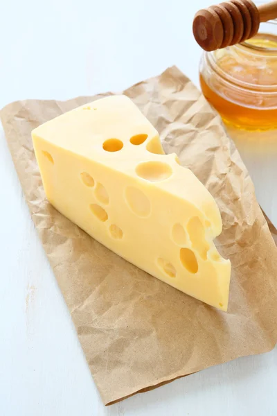 Cheddar cheese on a paper with honey — Stock Photo, Image