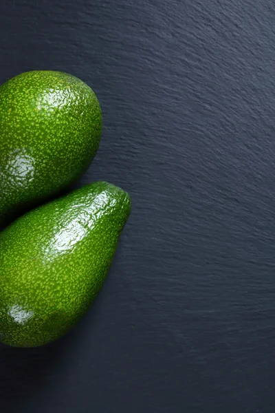 Green avocados on slate — Stock Photo, Image