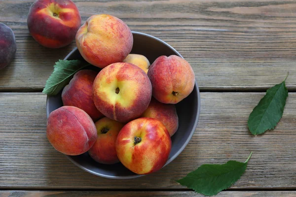 Fresh peaches in bowl on boards — Stock Photo, Image