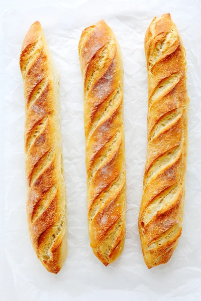 Fresh baguette on white paper — Stock Photo, Image