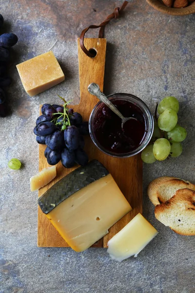 Queijo com engarrafamentos e uvas — Fotografia de Stock