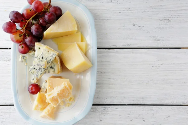 Käse und rote Trauben auf dem Teller — Stockfoto