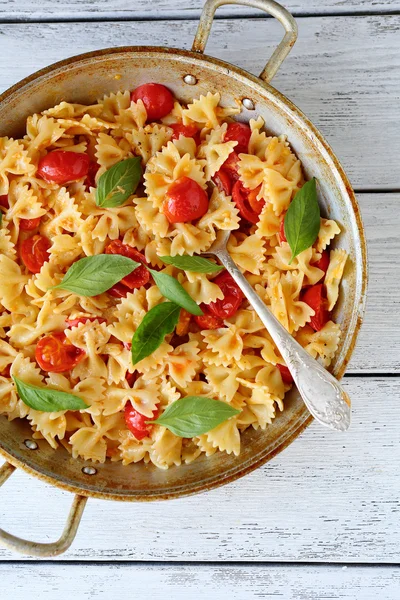 Pasta with tomatoes and basil in pan — Stock Photo, Image