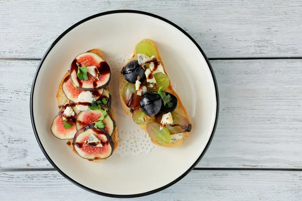 Two toasts with fruits and cheese — Stock Photo, Image