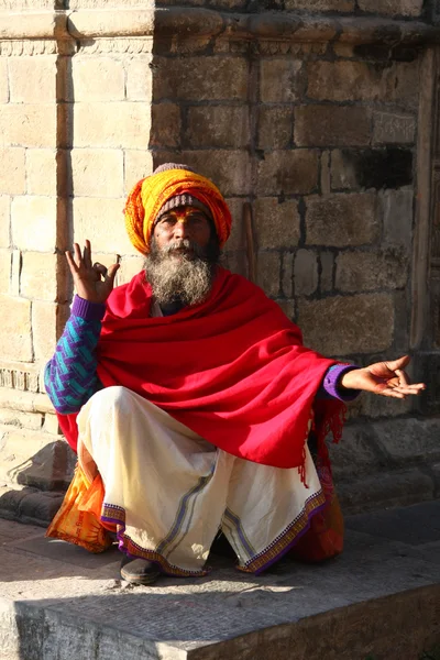 KATHMANDU, NEPAL-DECEMBER, 2009 - Неопознанный аскет или садху в храме Пашупатинатхи ждет путешественников Стоковое Фото