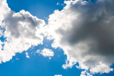 Avcılara benzer iki bulut güneşi emer. Kümülüs bulutları arasında mavi gökyüzü.