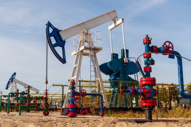 Petrol pompaları güneşli bir günde çalışır. Parlak renkli petrol pompaları petrol veya gaz üretir.