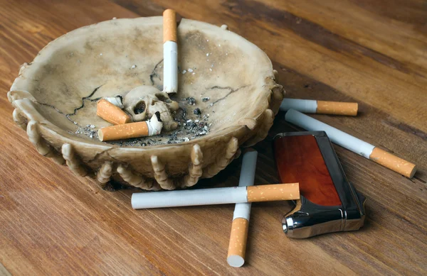 kül tablası, çakmak ve ahşap bir masa üzerinde Sigara