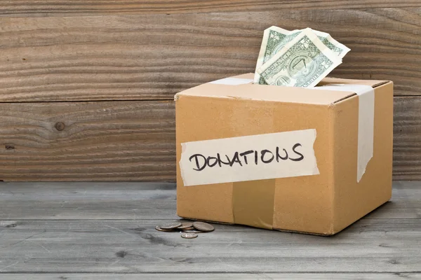 Caja de cartón de donación con billetes y monedas en dólares —  Fotos de Stock