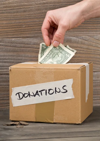 L'uomo mette denaro in donazioni scatola di cartone con banconota da un dollaro — Foto Stock
