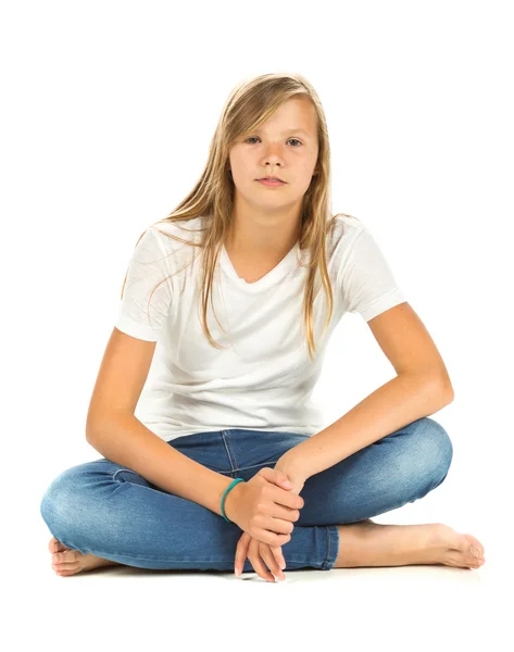 Junges Mädchen sitzt mit weißem T-Shirt und blauer Jeans über weißem — Stockfoto