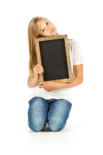 Junges Mädchen sitzt mit leerer Tafel vor weißem Hintergrund — Stockfoto