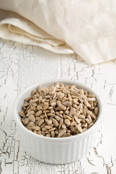 Gepeld zonnebloempitten in kom op rustieke witte tafel — Stockfoto