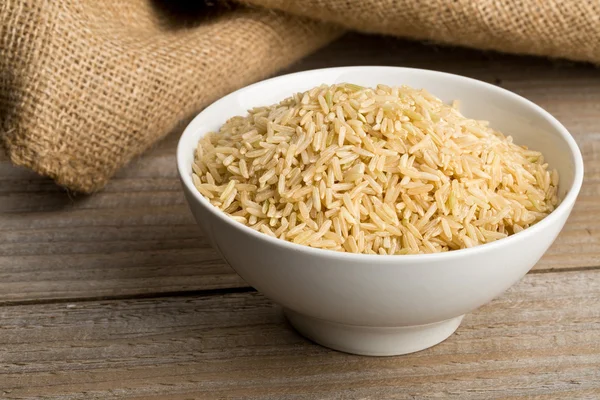 Natural brown uncooked rice in white bowl — Stock Photo, Image