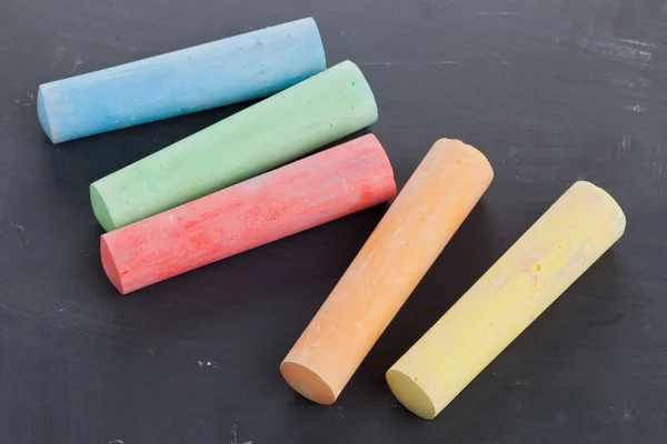 Colorful pieces of chalk on blackboard — Stock Photo, Image