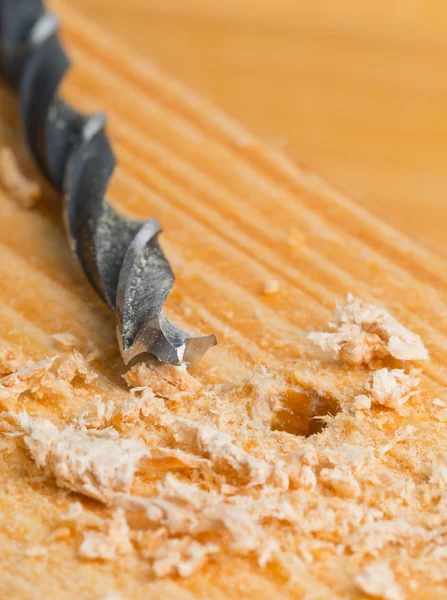 Wood drill on wooden surface with chips — Stock Photo, Image