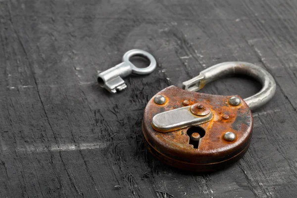 Open antique padlock with key on black — Stock Photo, Image