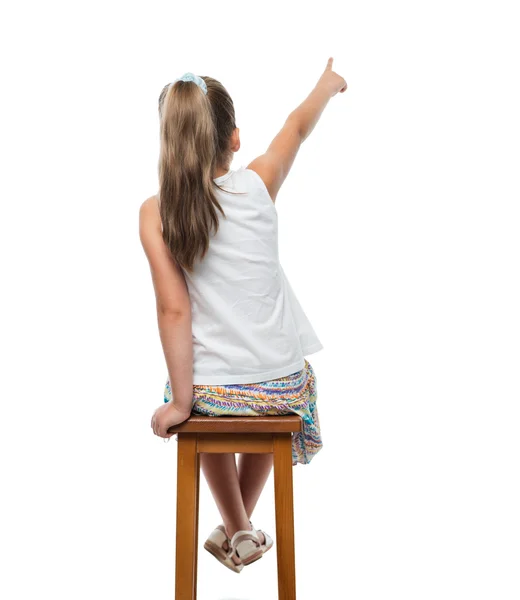 Маленькая девочка сидит на стуле и указывает в сторону Стоковое Изображение
