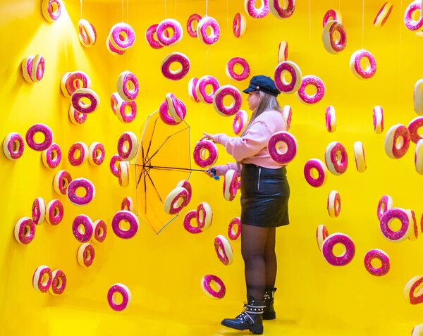 a young woman with umbrella between flying donuts