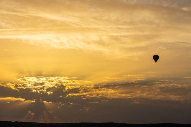 Sıcak hava balonu gökyüzünde turuncu gündoğumu bulutlarıyla